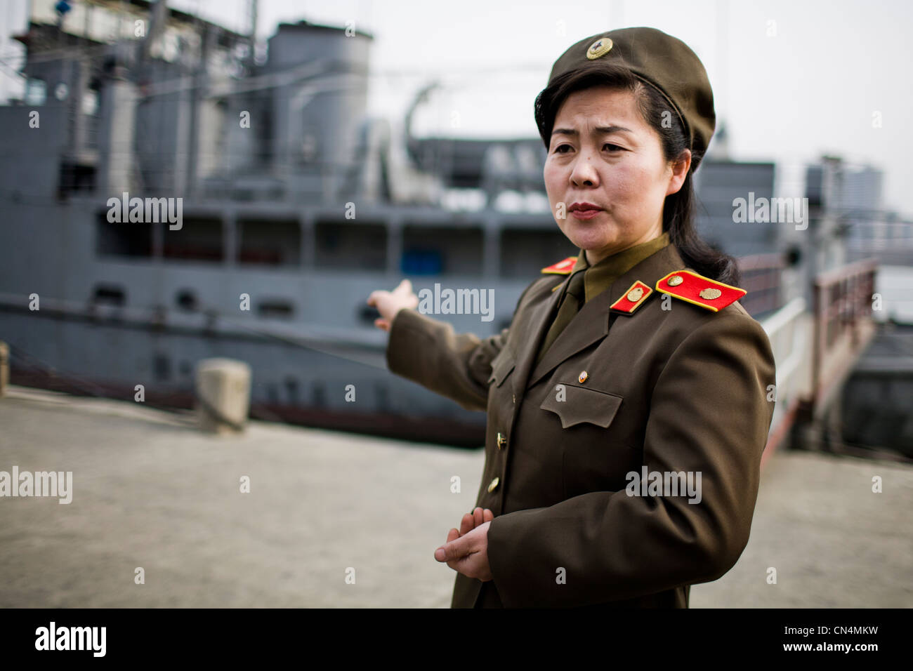 Corea del Nord Pyongyang, femmina nord coreano ufficiale militare che mostra il modo in cui la USS Pueblo mostra, una nave Americana Foto Stock