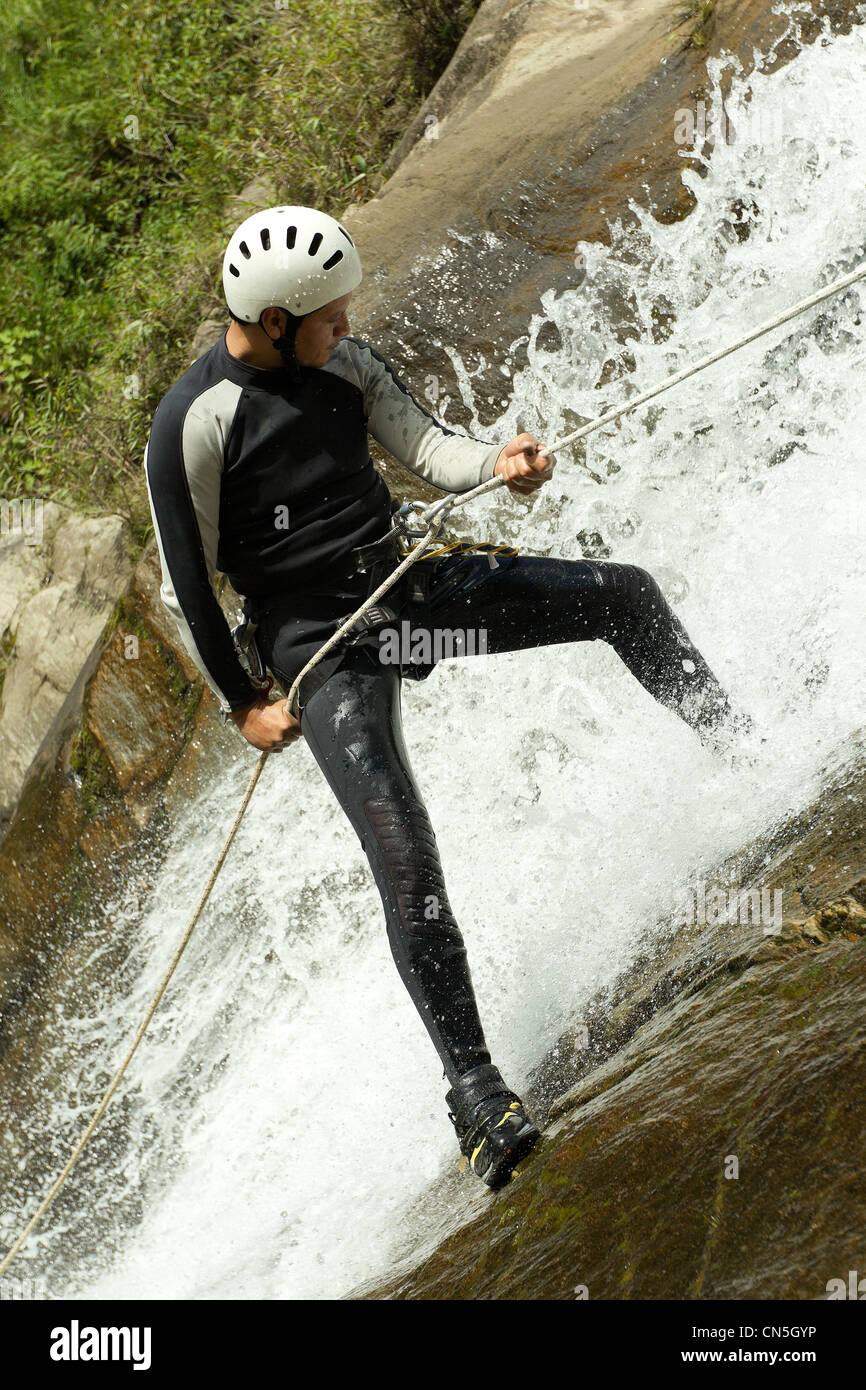 Uomo adulto scendendo una cascata ecuadoriana in una posizione corretta Foto Stock