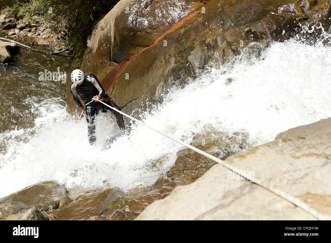 Uomo adulto scendendo una cascata ecuadoriana in una posizione corretta Foto Stock