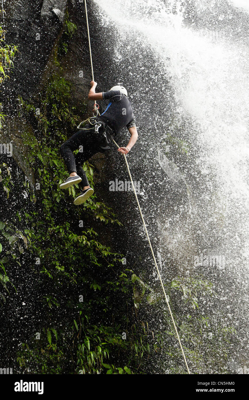 Uomo che discende un enorme cascata In ecuadoriana foresta di pioggia Foto Stock