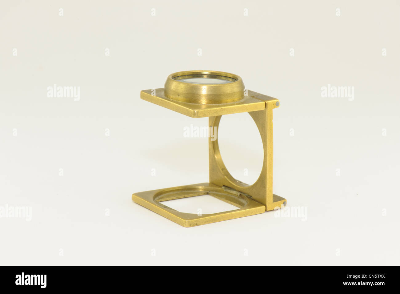 Lente di ingrandimento ottone preso su sfondo bianco tester di lino in vecchio stile Foto Stock