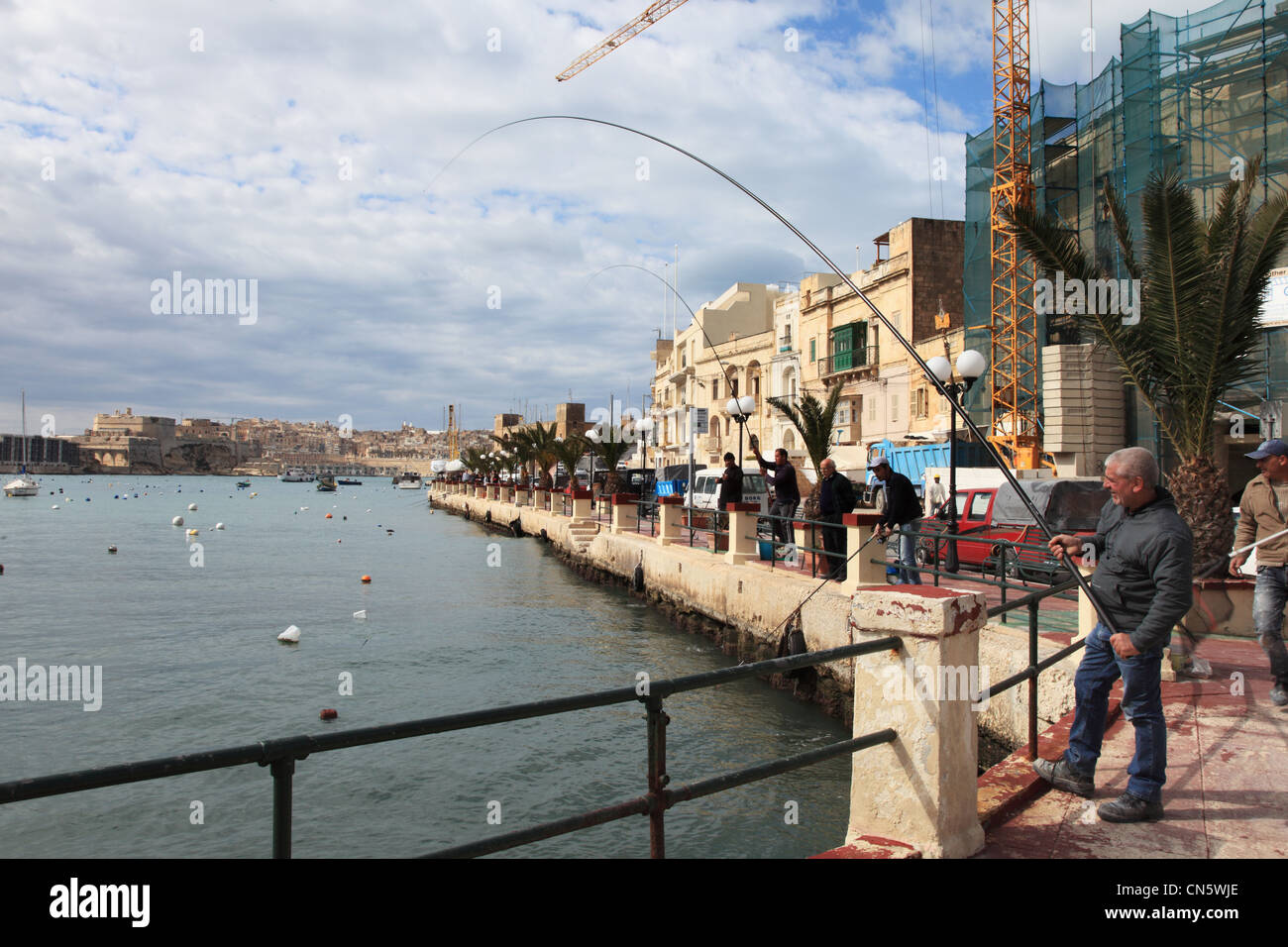 L'uomo le catture di pesce usando un'asta e una linea all'interno della baia Kalkara Malta Europa Foto Stock