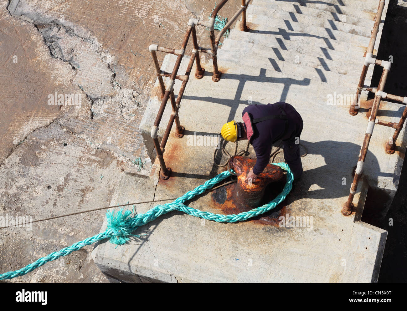 Un lavoratore di porta fissa la linea di ormeggio del Gozo a Malta ferry a Cirkewwa Malta terminale. Foto Stock
