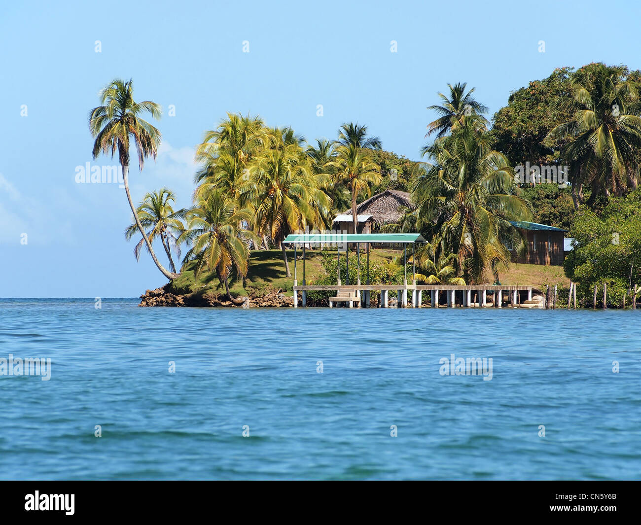 Isola tropicale con palme da cocco e un dock che conduce ad un piccolo villaggio, America Centrale, arcipelago di Bocas del Toro, Panama Foto Stock