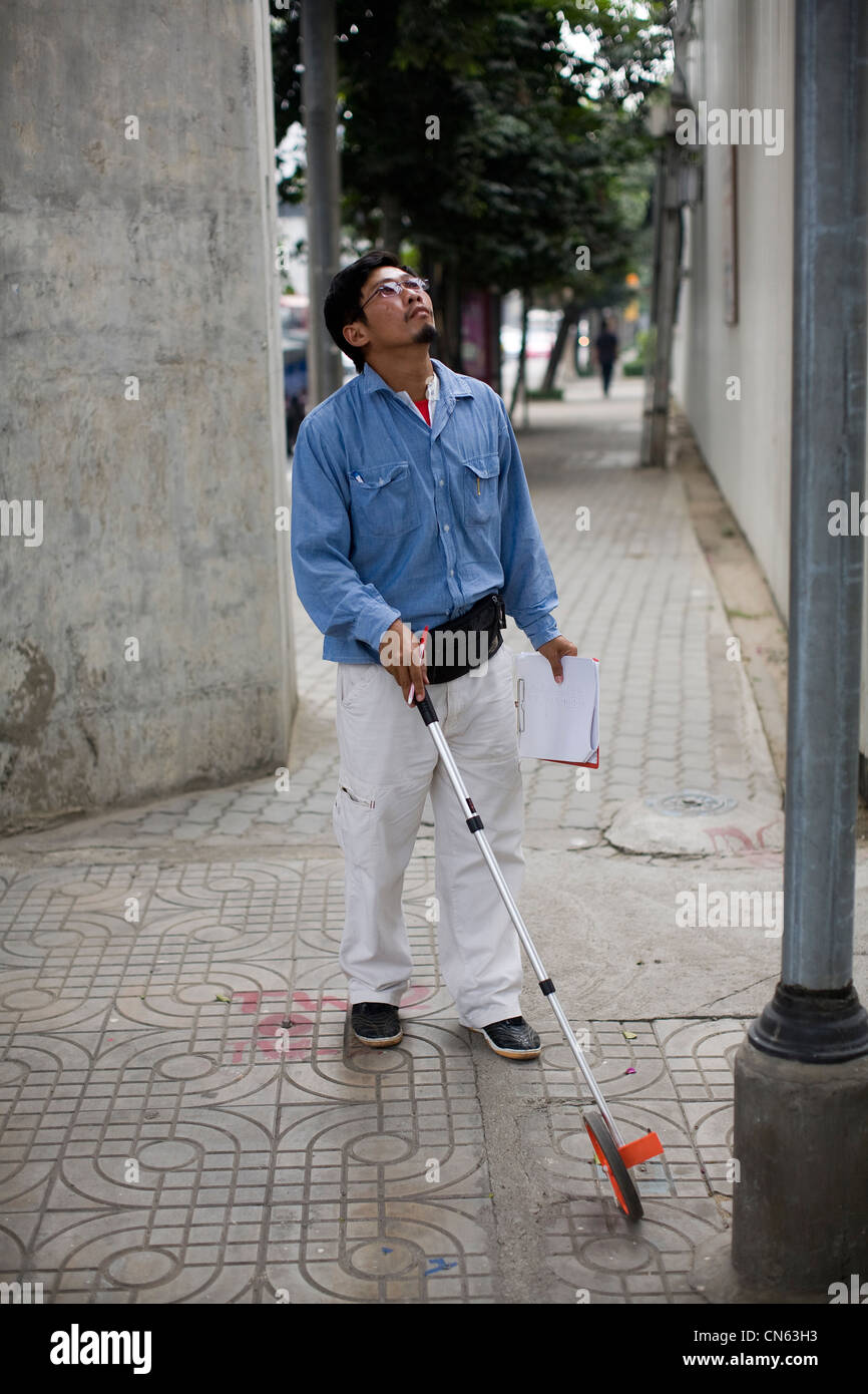 Un urbano maintence lavoratore con una distanza ruota di misurazione, Bangkok, Thailandia Foto Stock