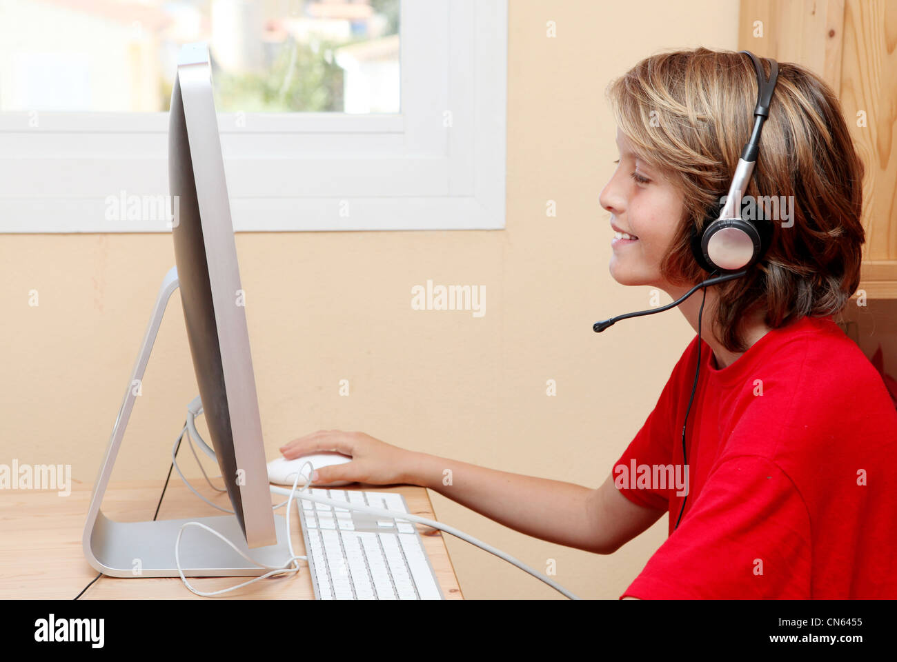 Bambino con cuffie o auricolari per ascoltare musica o conversare sulla home  o pc della scuola computer Foto stock - Alamy