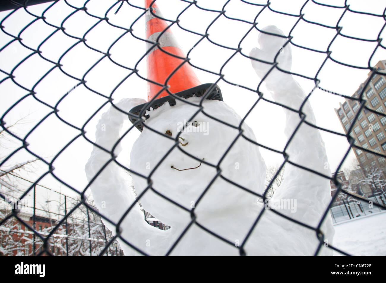 Un felice pupazzo di neve dietro una catena collegamento recinto. Foto Stock
