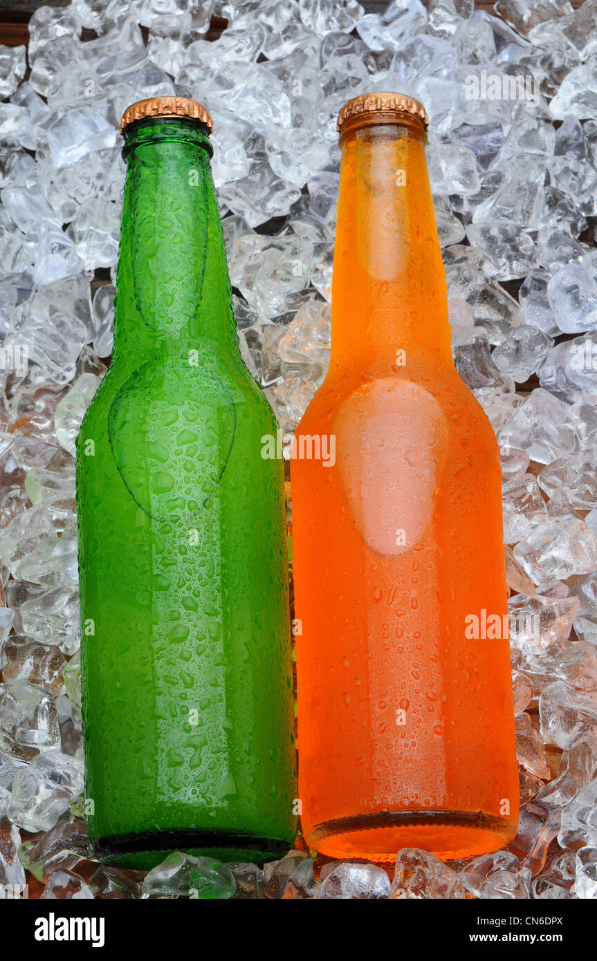 Due bottiglie di soda su un letto di ghiaccio. Arancio e limone calce soft drinks con condensazione in formato verticale. Foto Stock