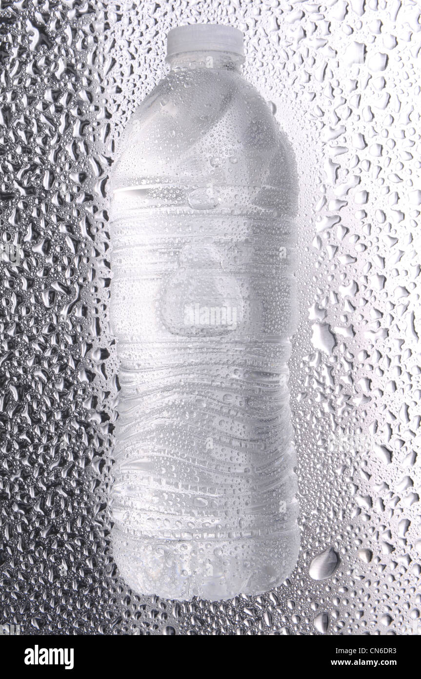 Acqua in bottiglia recante sul suo lato su una superficie di metallo ricoperta in gocce d'acqua. Foto Stock