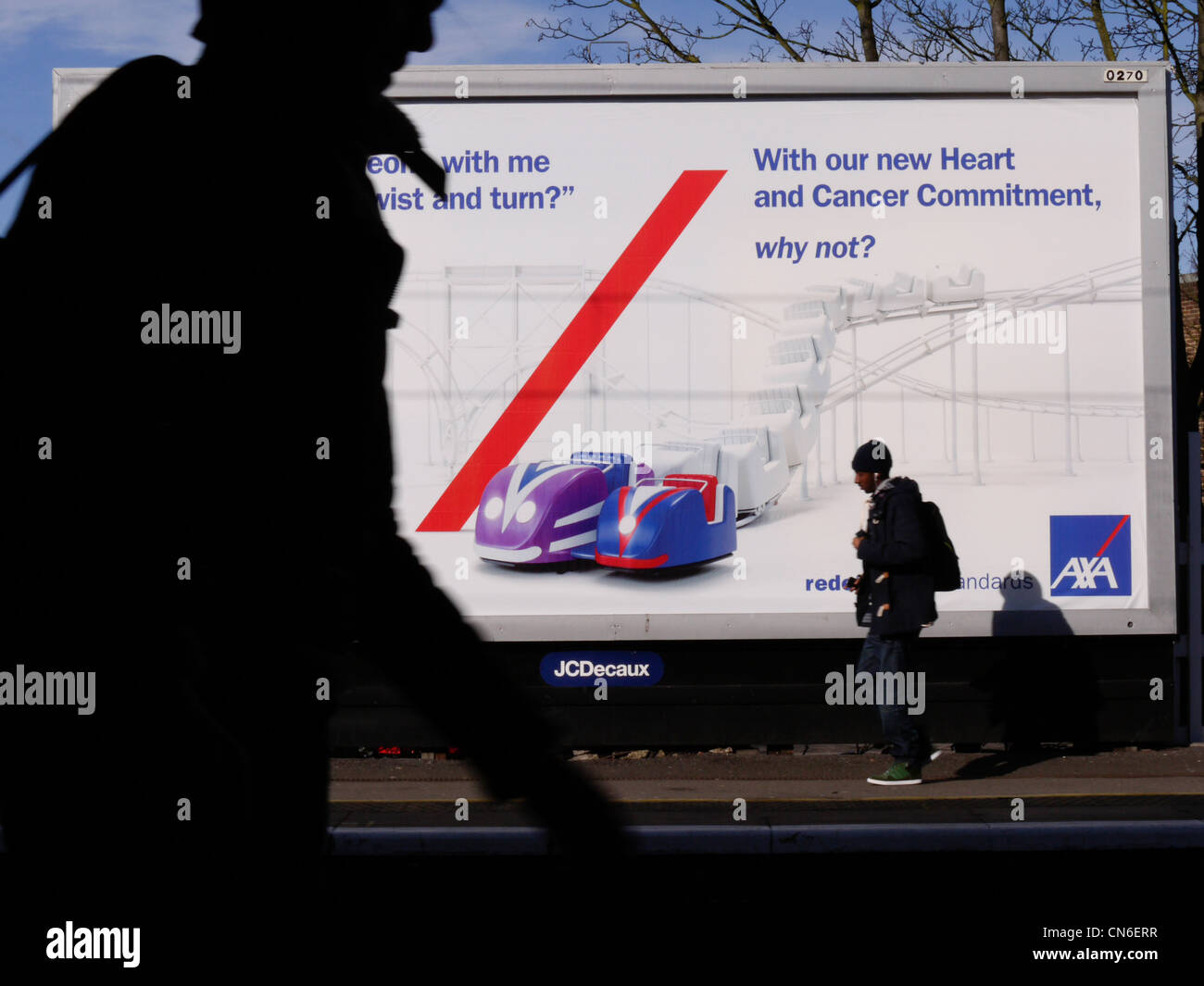 I passeggeri passano accanto al cartellone pubblicitario JC Decaux AXA nel nord-est di Londra, Regno Unito, con un'esposizione di poster di rilievo su un deposito ferroviario. Foto Stock