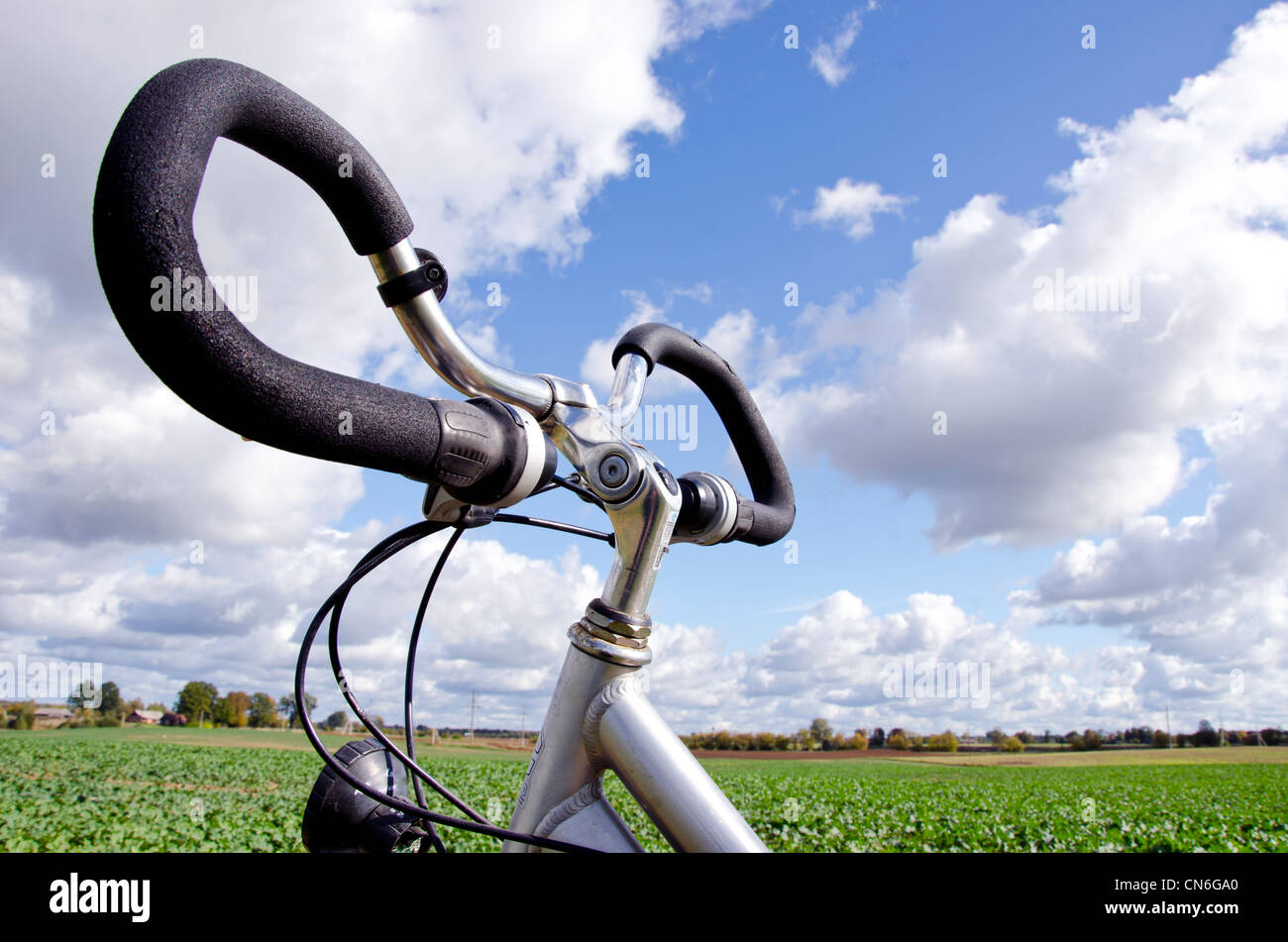 Manubrio di bicicletta closeup su sfondo blu del cielo nuvoloso. Veicolo non richiedono combustibile. Attivo nelle persone sane il trasporto. Foto Stock