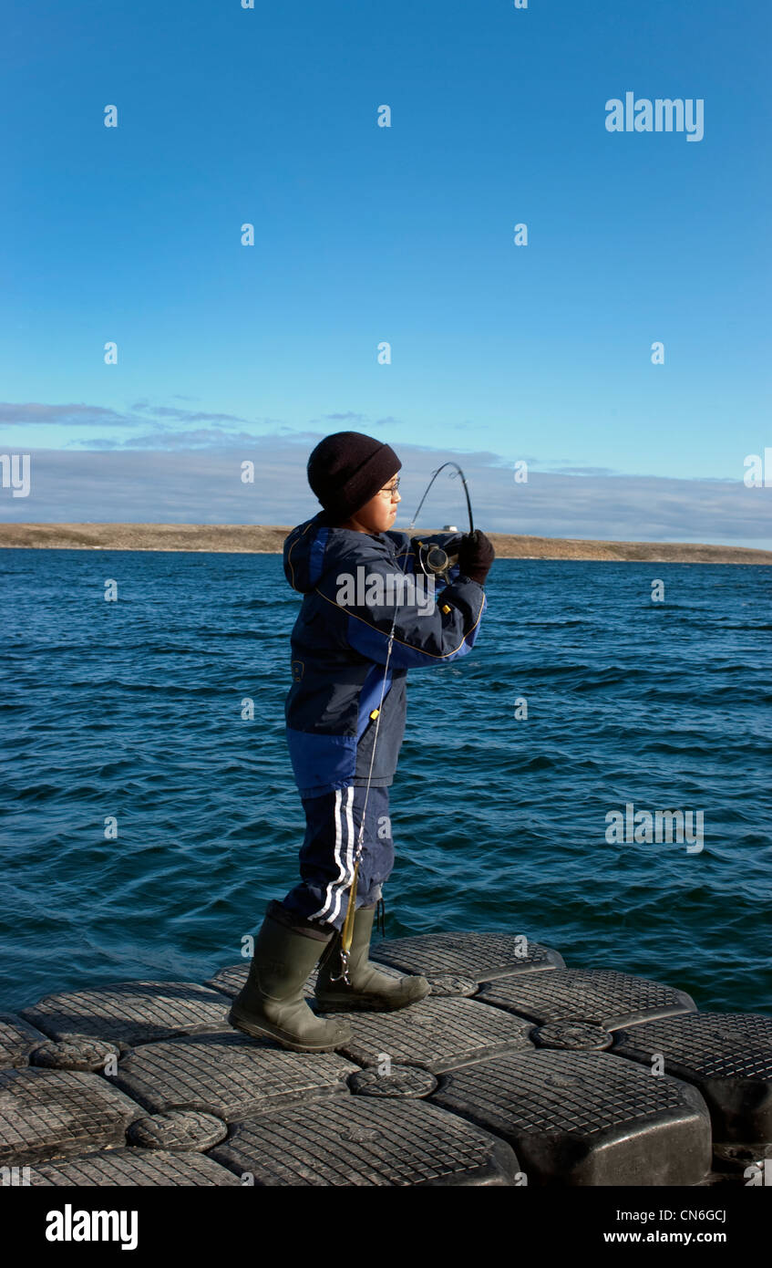 Ragazzo sul dock per colata salmerino, Cambridge Bay, Nunavut Foto Stock