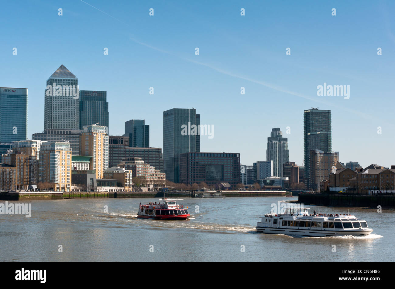 Le imbarcazioni turistiche andare oltre il Canary Wharf skyline di Londra, Inghilterra. Foto Stock
