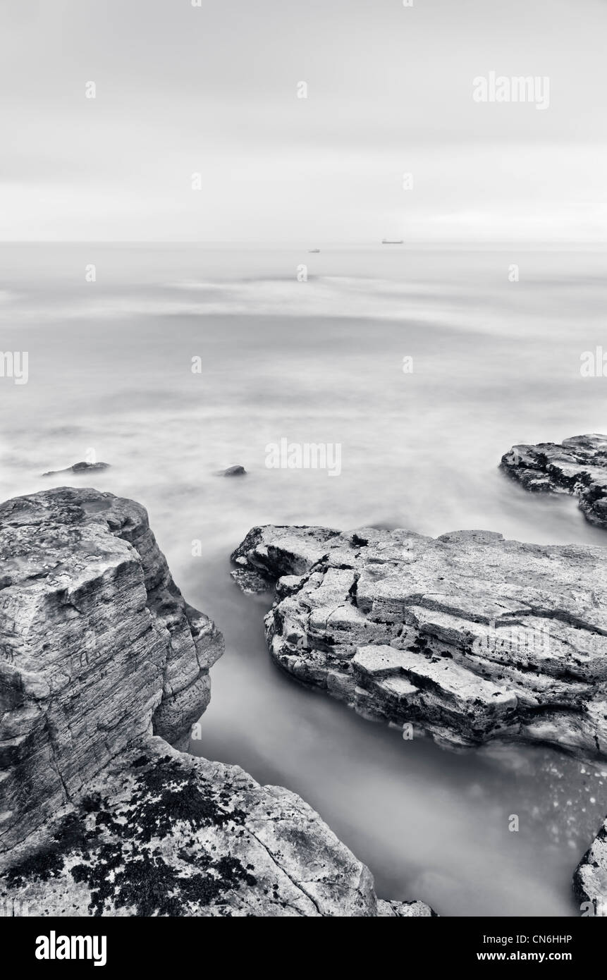 Le rocce su un mare liscio Foto Stock