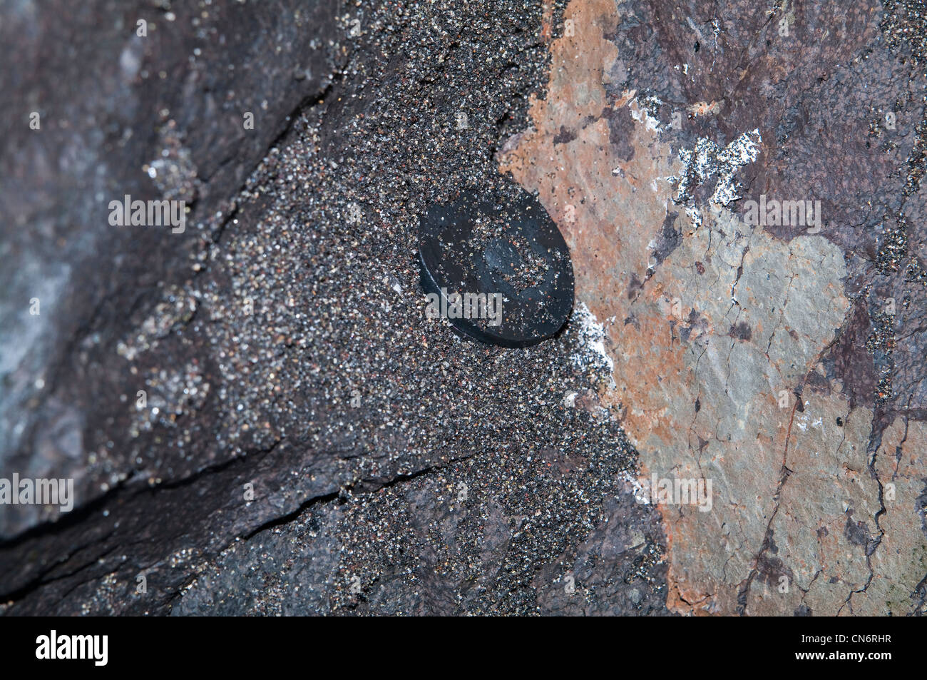 Geocache mimetizzate nascoste in un muro di roccia all'interno di una grotta, che si fonde con le consistenze di pietra naturale. Foto Stock