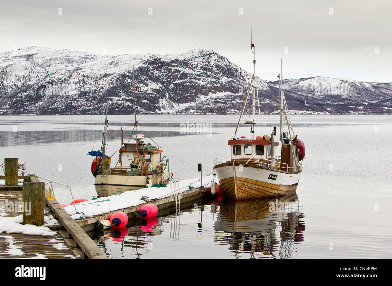 2 barche legata a un molo su un fiordo con montagne innevate dietro presi in formato orizzontale Foto Stock