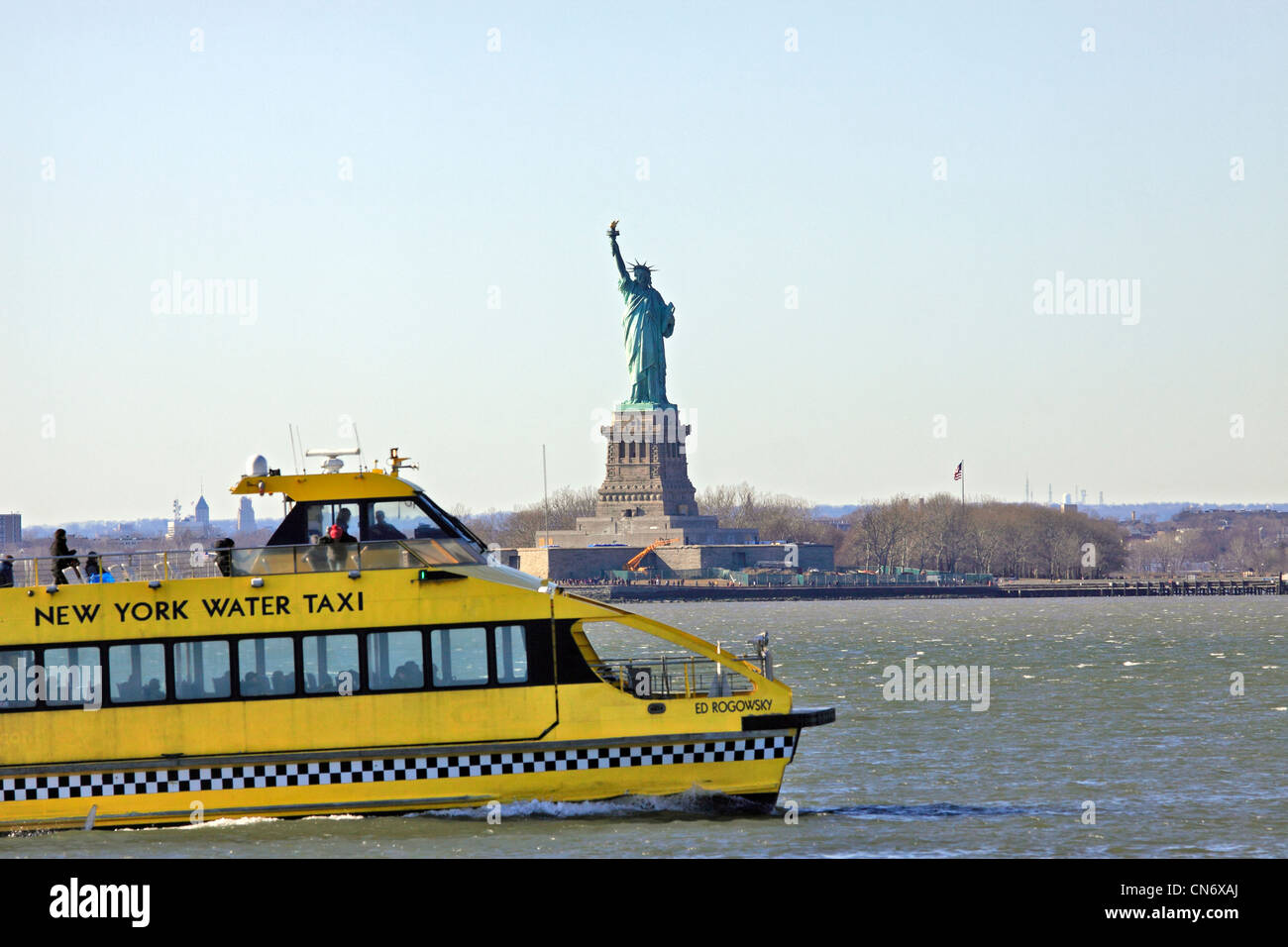 A New York Water Taxi passa davanti alla statua della libertà nel porto di New York Foto Stock