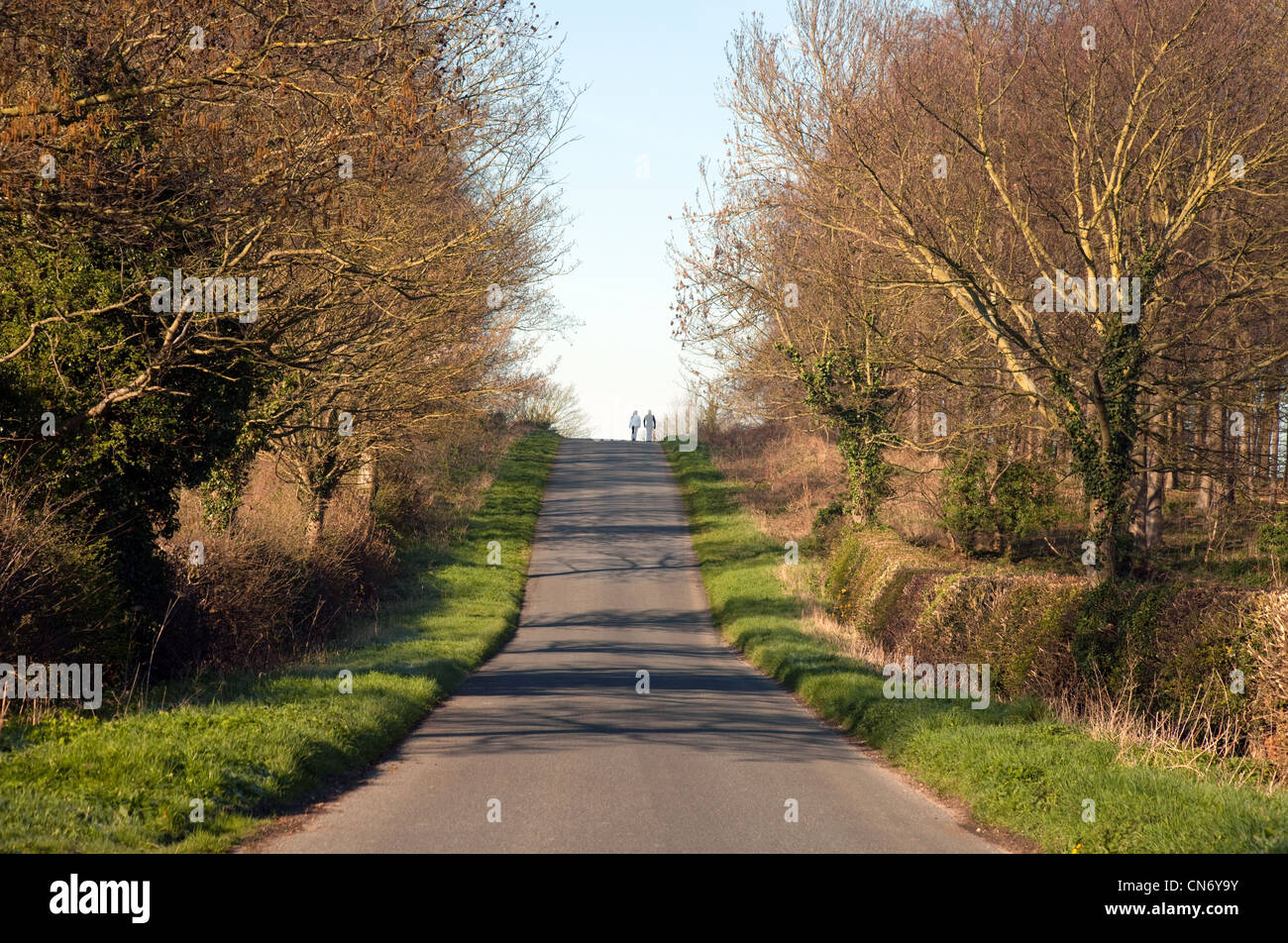 Un giovane a camminare su una strada di campagna in primavera, Cambridgeshire East Anglia UK Foto Stock