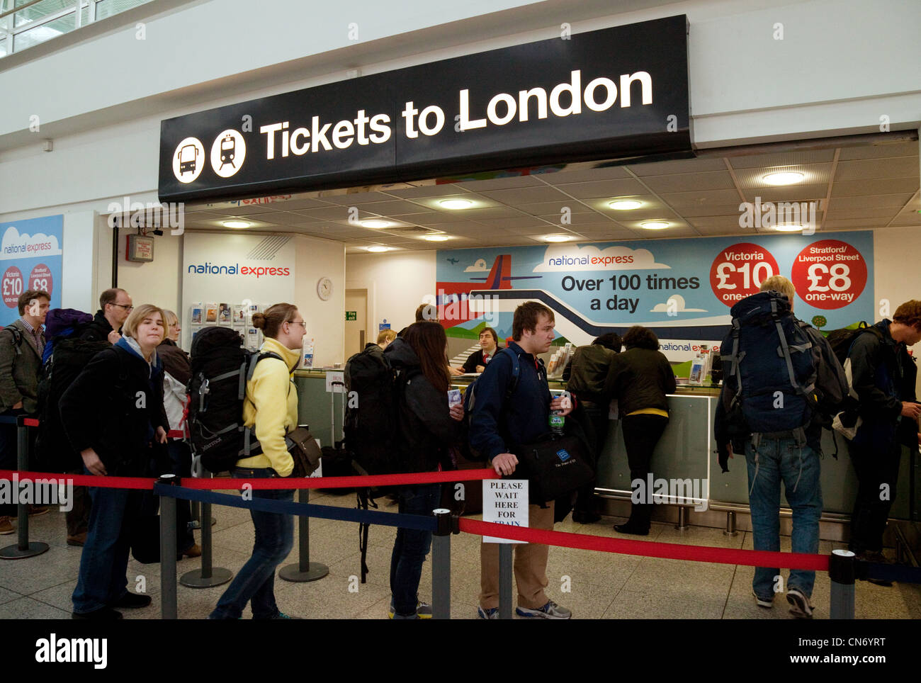 Aria i viaggiatori che arrivano all'aeroporto di Stansted coda per i biglietti per Londra Stansted Aeroporto Essex REGNO UNITO Foto Stock