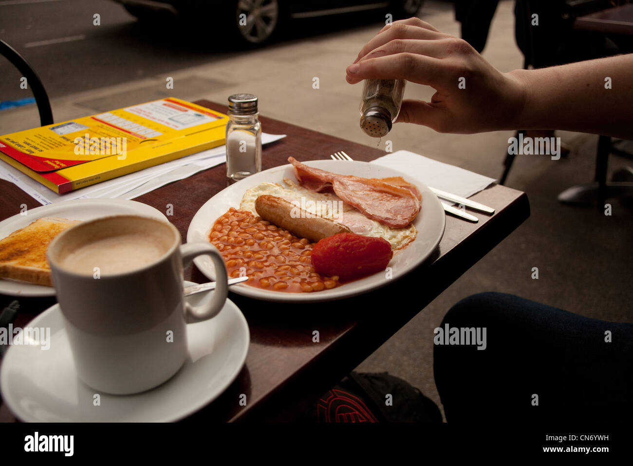 Un uomo mangia una tradizionale prima colazione inglese al di fuori di un cafe in Londra England Regno Unito Foto Stock