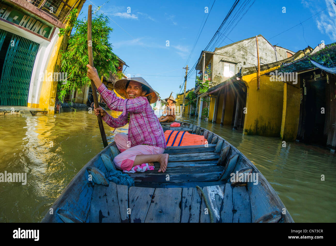 Sorridente ragazza vietnamita righe attraverso strade allagate dalla barca, Hoi An, Vietnam Foto Stock