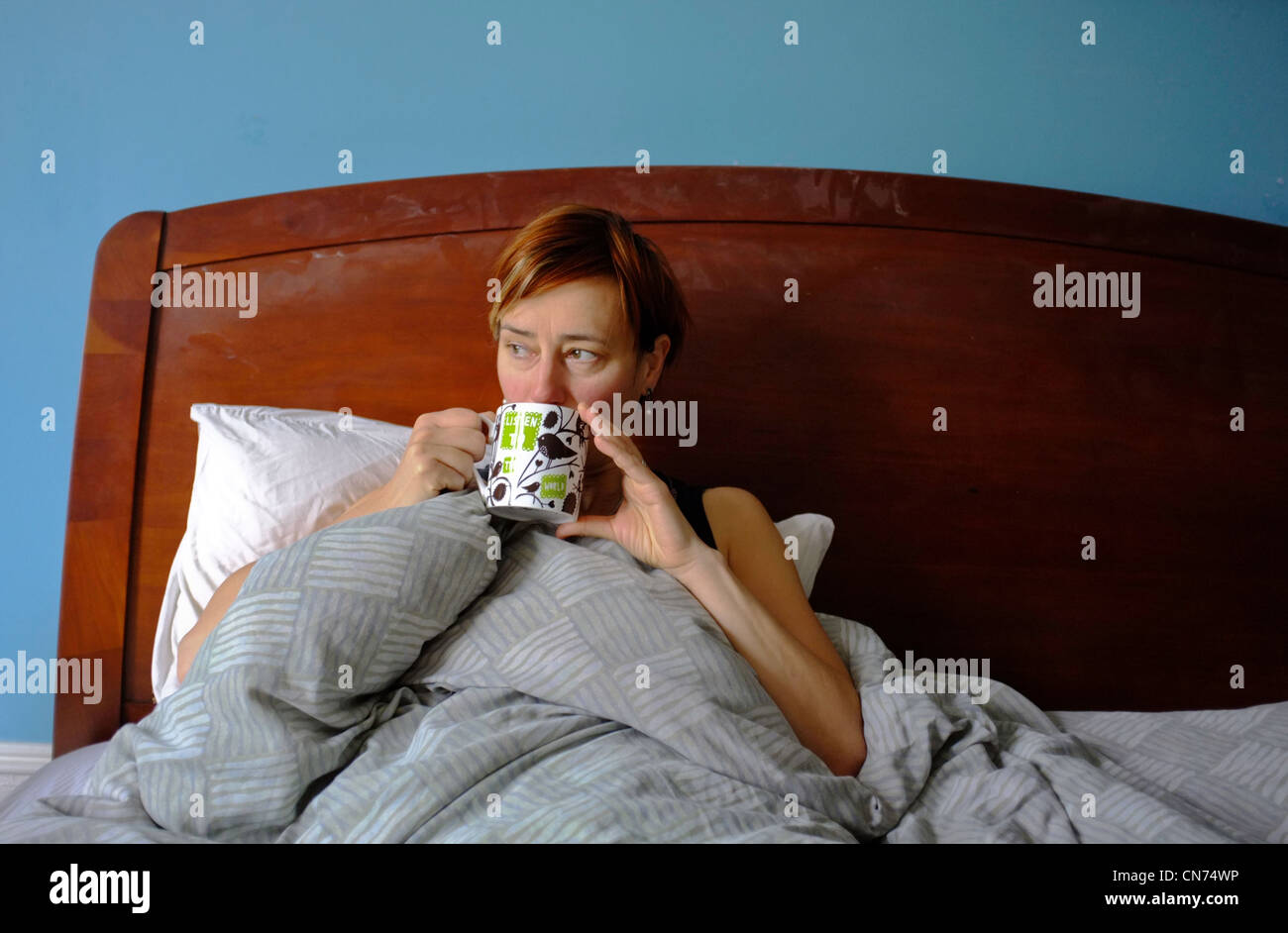 Una donna di mezza età bere il tè a letto Foto Stock