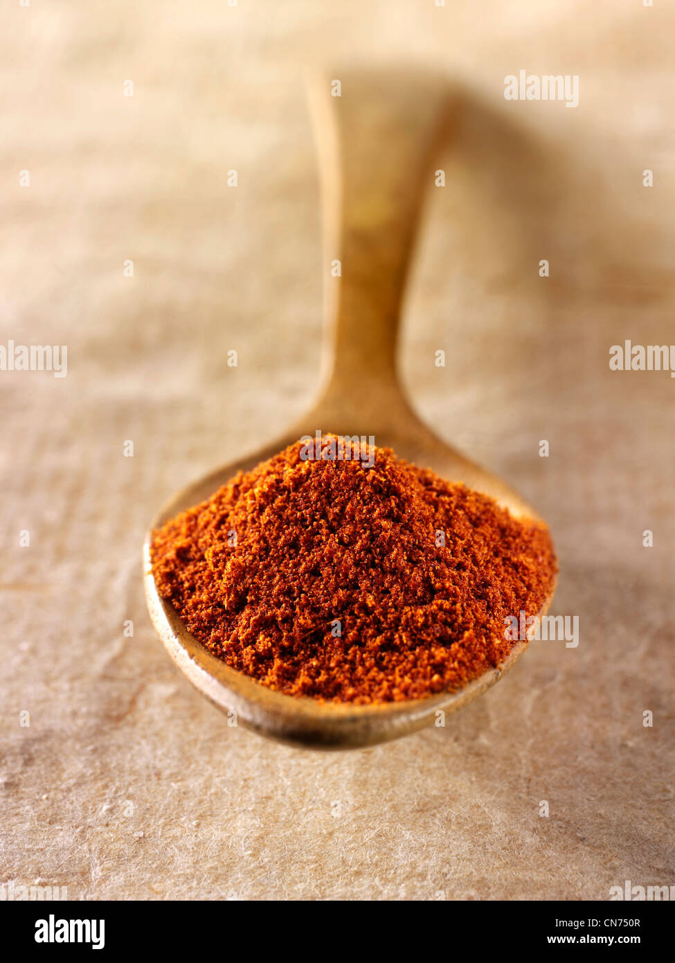 La paprika spice powderin un cucchiaio di legno contro uno sfondo naturale Foto Stock
