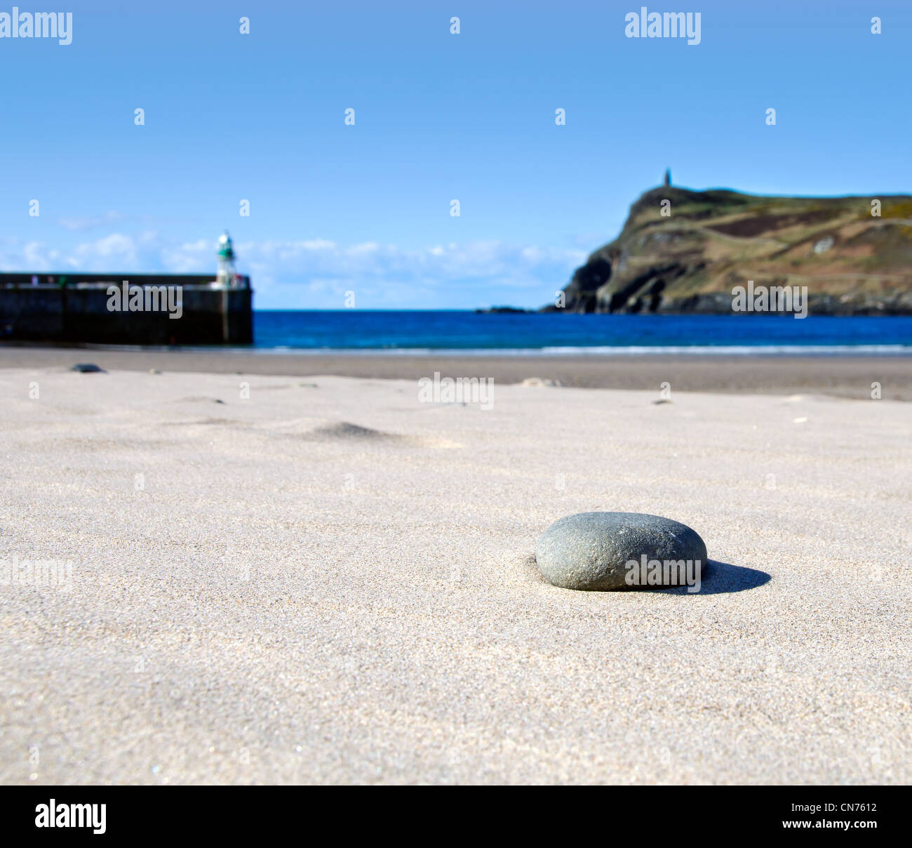 Dettaglio della pietra su una spiaggia di sabbia con lighhouse e torre in background. Port Erin - Isola di Man. Messa a fuoco poco profonda Foto Stock