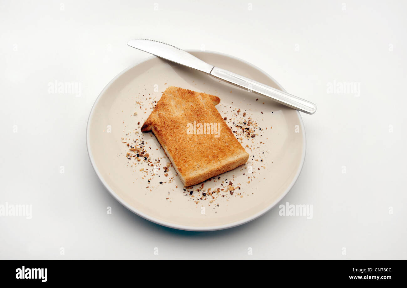 Pezzo di pane tostato in forma di casa sulla piastra con coltello alloggiamento nuovamente la proprietà di mercato di acquistare casa gli acquirenti prima volta case costa ETC REGNO UNITO Foto Stock