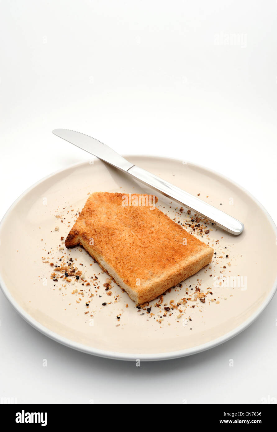 Pezzo di pane tostato in forma di casa sulla piastra con coltello alloggiamento nuovamente la proprietà di mercato di acquistare casa gli acquirenti prima volta case costa ETC REGNO UNITO Foto Stock