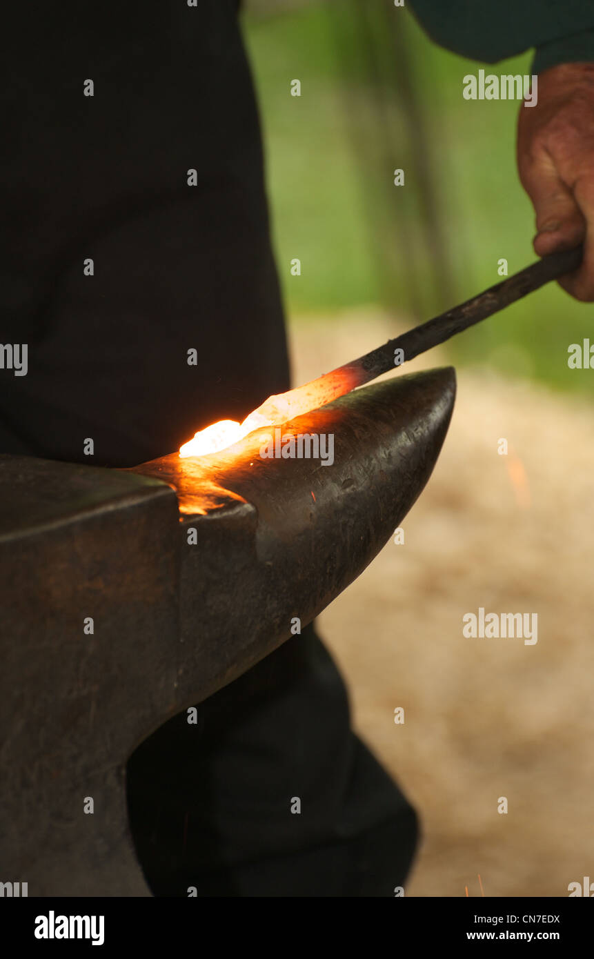 Un fabbro lavora red ferro caldo su un'incudine. Foto Stock