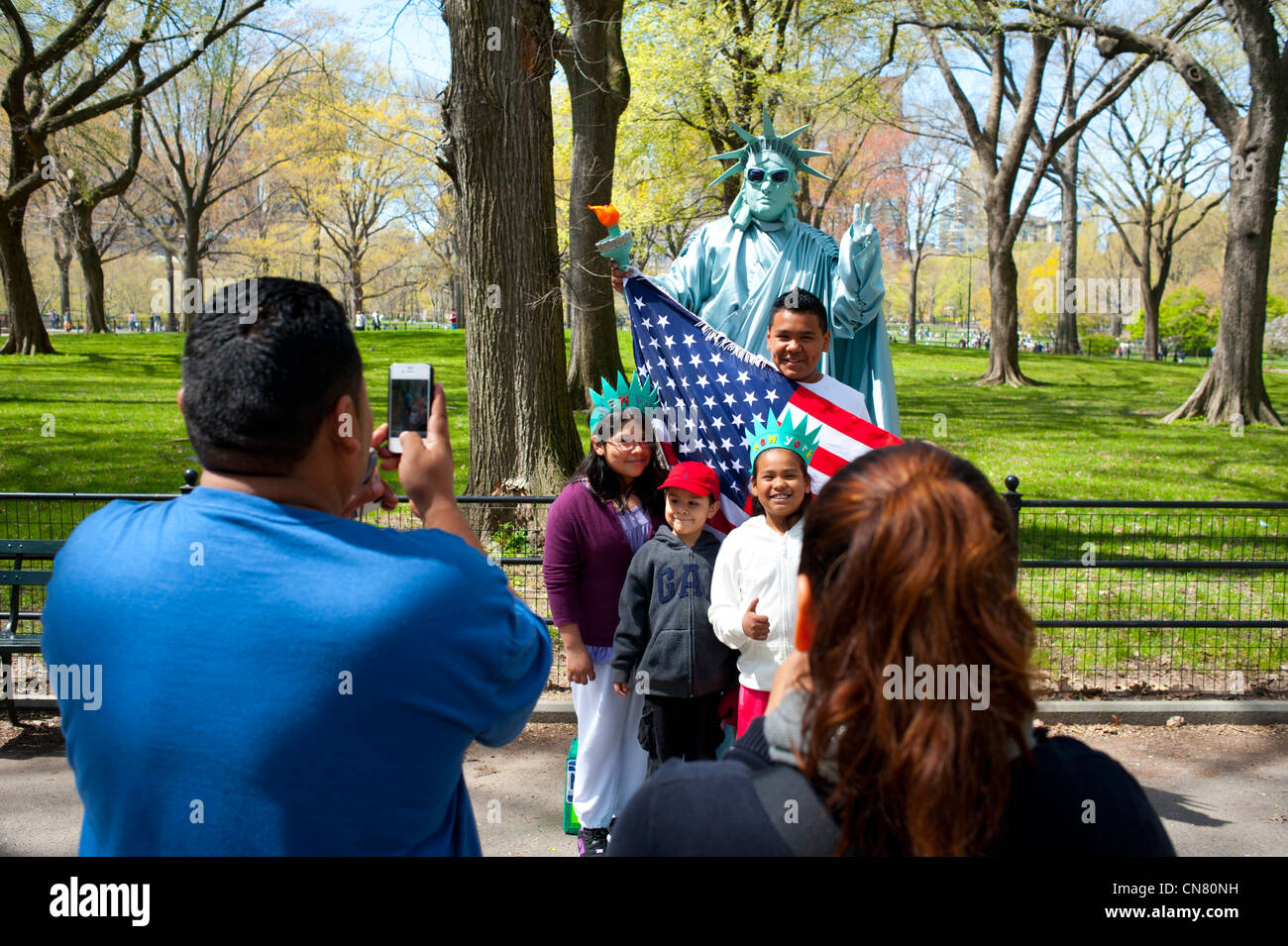 Stati Uniti d'America New York City New York NY Manhattan Central Park - famiglia ispanica pone con un essere umano la Statua della Libertà e la bandiera americana Foto Stock