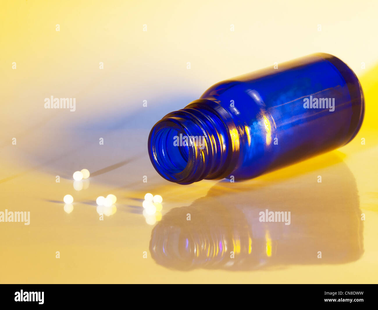 Aprire una piccola bottiglia di colore blu sulla massa riflettente con globuli intorno Foto Stock
