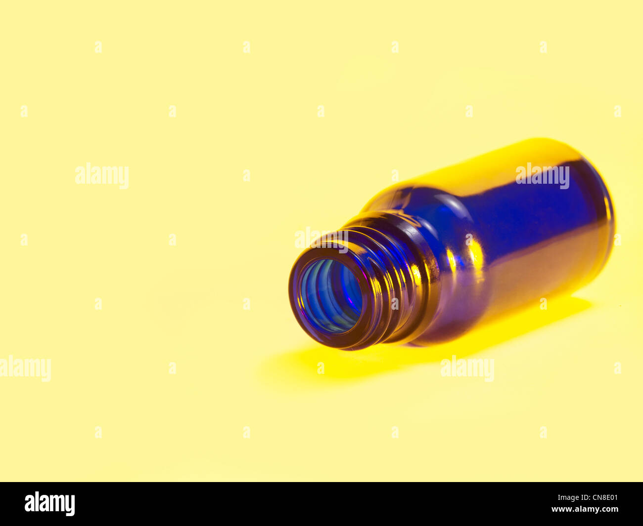 Aprire una piccola bottiglia di colore blu in luce posteriore giallo Foto Stock