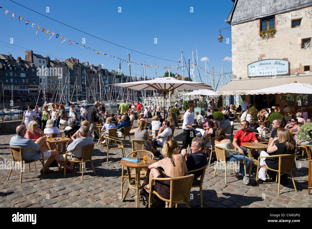 Francia, Calvados, Honfleur, La Maison Bleue ristorante e i clienti seduti sulla terrazza con il vecchio porto in background Foto Stock