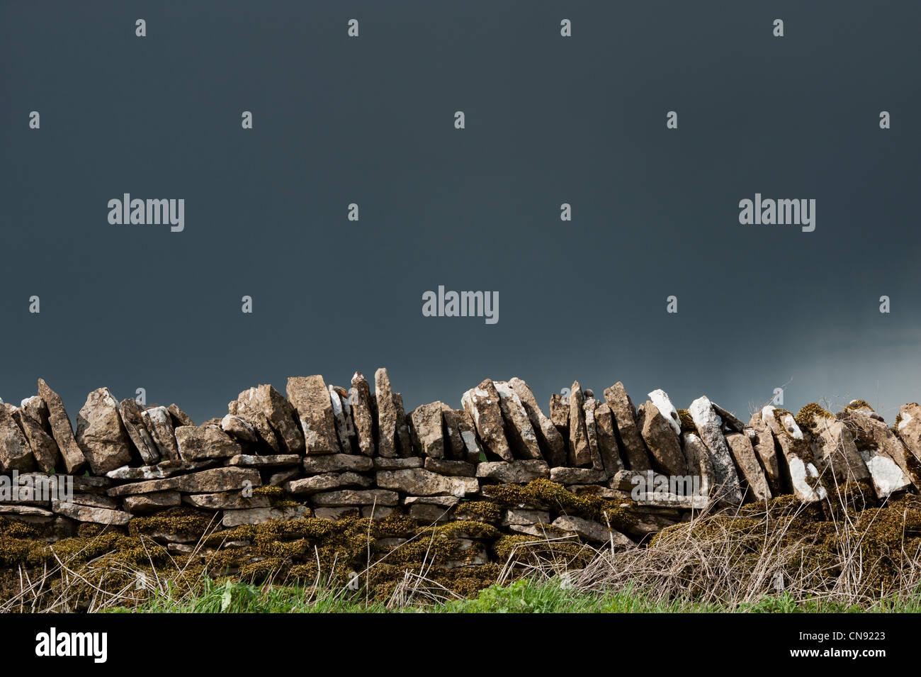Stormy pioggia nuvole sopra il vecchio secco muro di pietra nella campagna inglese Foto Stock