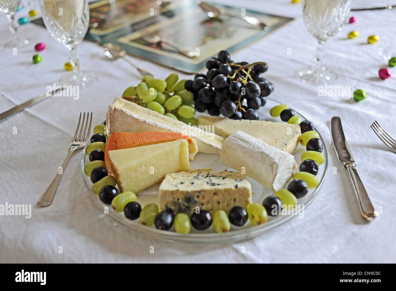 Altopiano di formaggio o la piastra ad un tavolo per la cena con uve posizionati intorno al bordo Foto Stock
