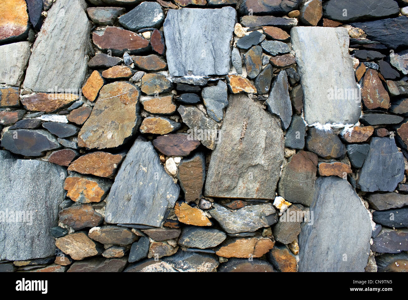 Un antico muro di pietra texture con rocce di varie forme e dimensioni. Foto Stock