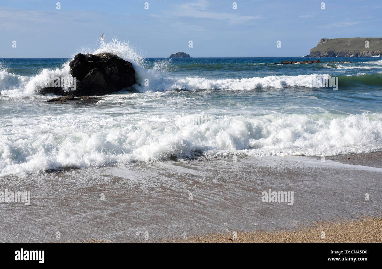 Rulli di rottura su una roccia solitaria, cielo blu, bianco crested onde su una spiaggia della Cornovaglia Foto Stock