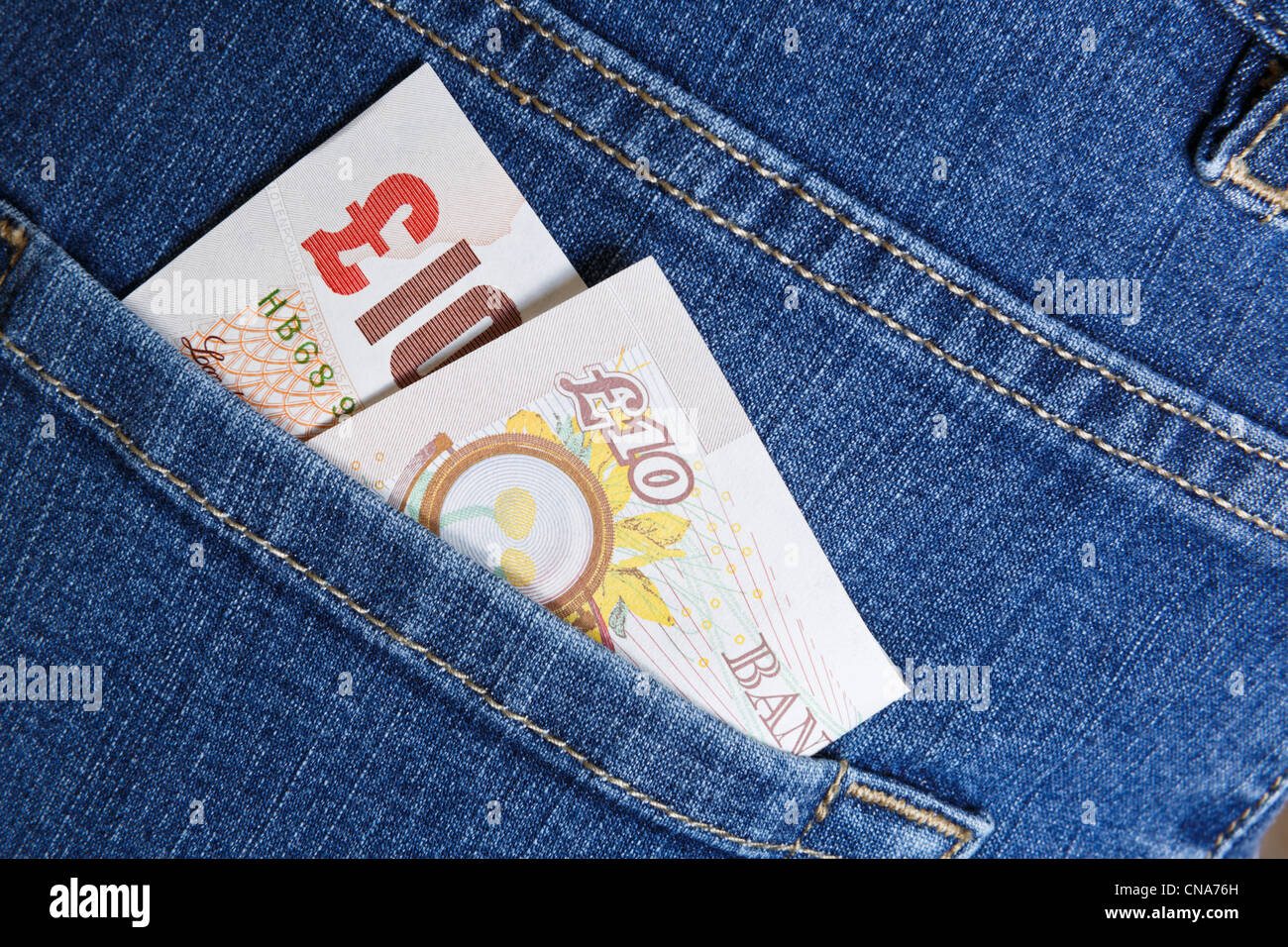 Regno Unito denaro dieci sterling pound nota GBP contanti in una tasca posteriore di un paio di blue jeans denim per illustrare un concetto di stile di vita. In Inghilterra La Gran Bretagna Foto Stock