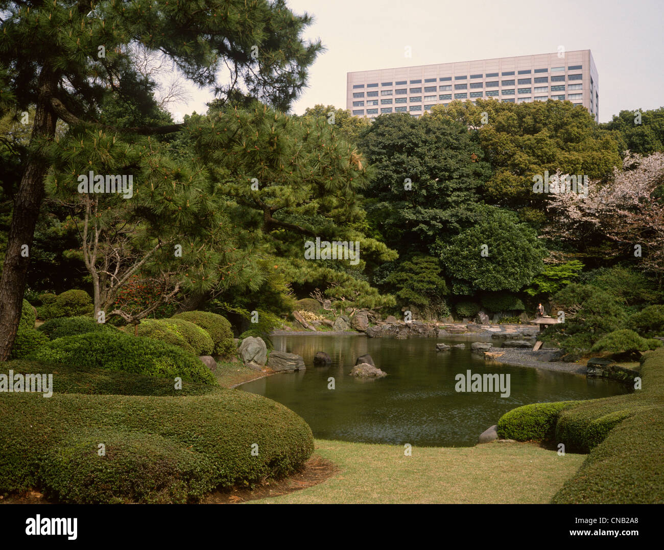 Giappone Tokyo Imperial Palace giardino con laghetto ornamentale edificio per uffici al di là Foto Stock