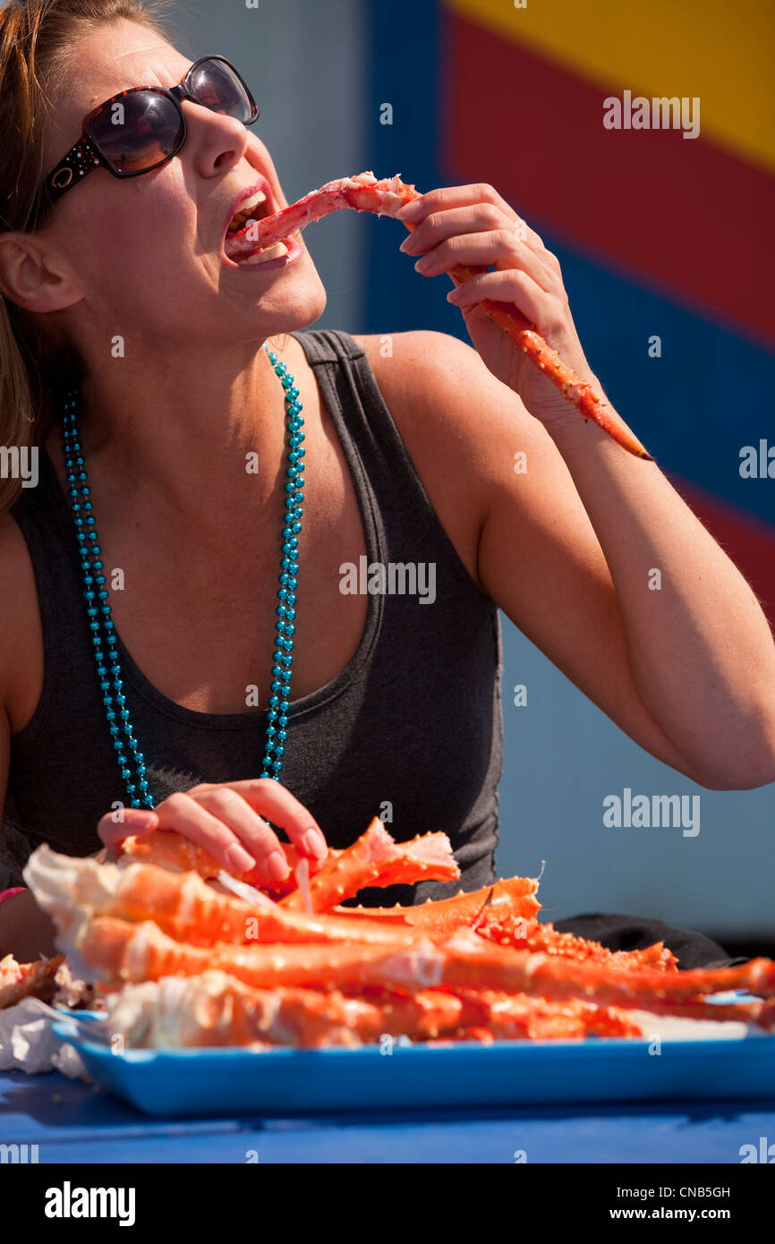 Donna di mangiare King crab gambe durante il Kodiak Alaska annuali di primavera Festival di granchio, isola di Kodiak, Southwest Alaska Foto Stock