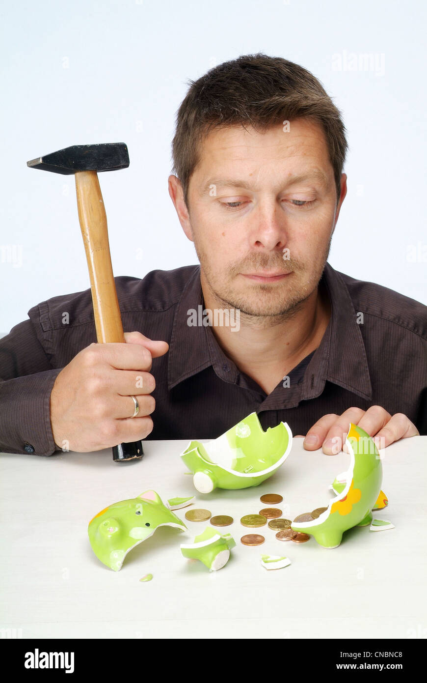 Un uomo in cerca deluso dopo lo sfondamento del suo piggybank Foto Stock