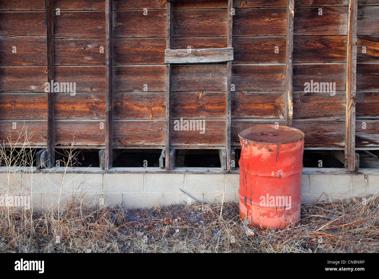 Vecchio arrugginito barile di petrolio e di legno stagionato muro del granaio Foto Stock