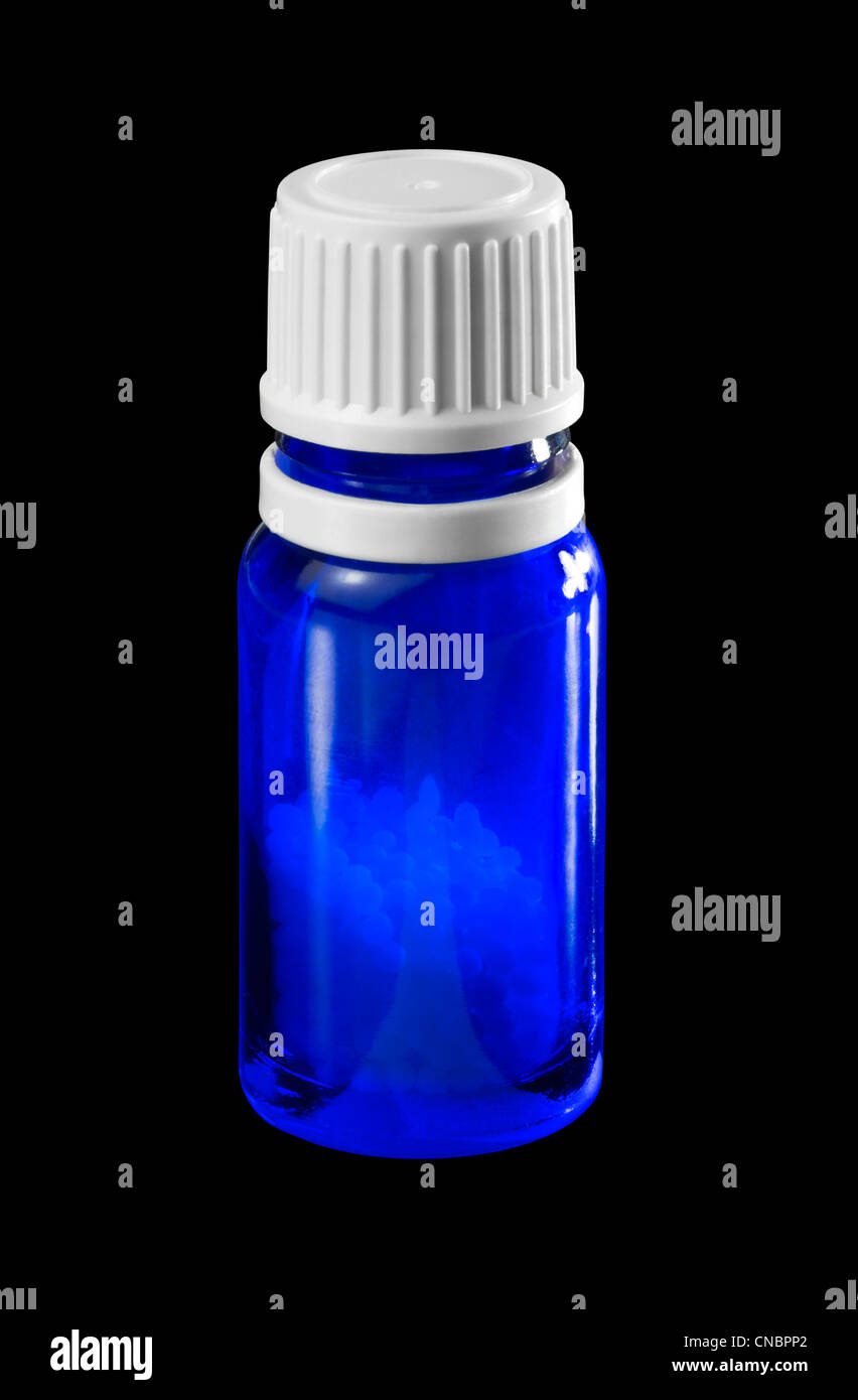 Una piccola bottiglia blu riempita con globuli Foto Stock