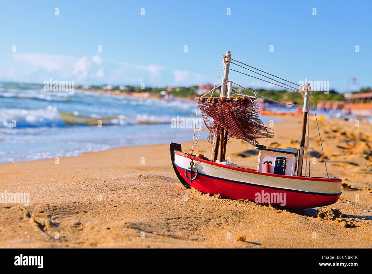 La piccola barca giocattolo sorge sulla spiaggia sabbiosa Foto Stock