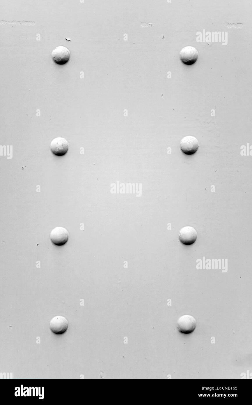 Un metallo verniciato texture di sfondo con quattro viti arrugginite o rivetti in bianco e nero. Foto Stock