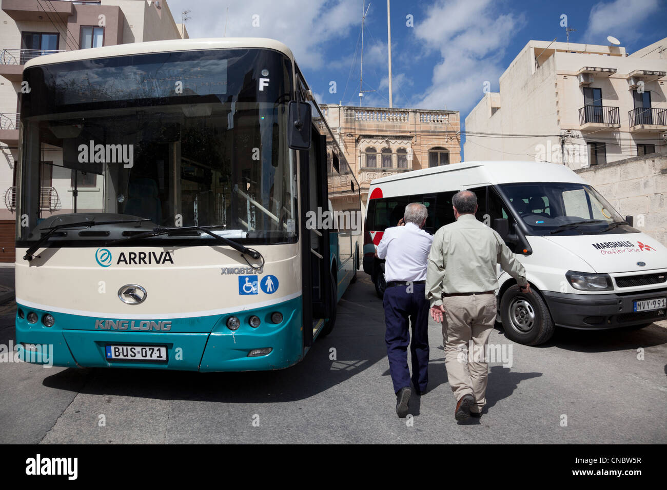 Bus driver tenta di ottenere aiuto, il suo bus intrappolati da un parcheggiato il mini bus mentre tenta di girare di Marsaxlokk, Malta. Foto Stock