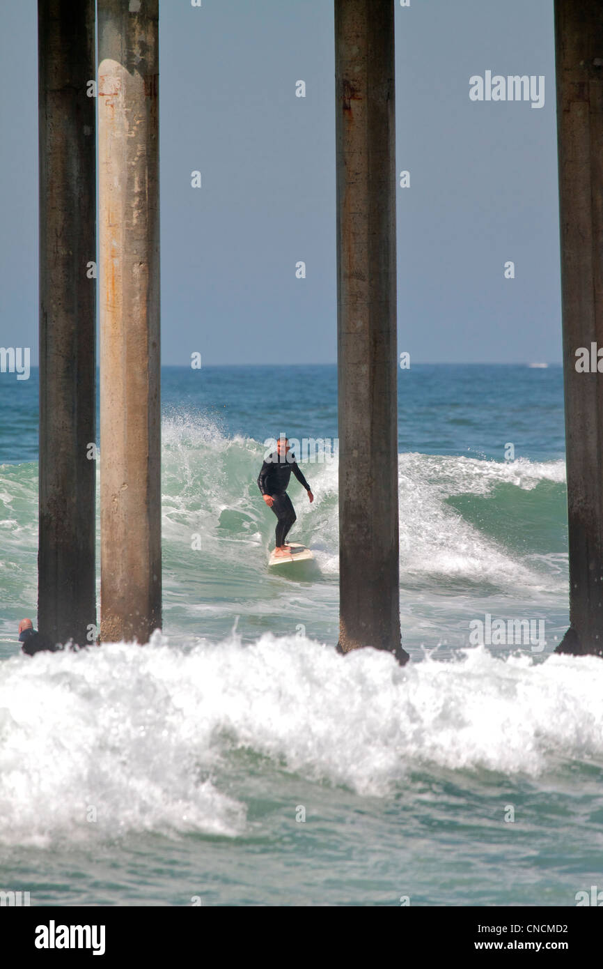 Huntington Beach Surfer a cavallo di un onda al presso il molo Foto Stock