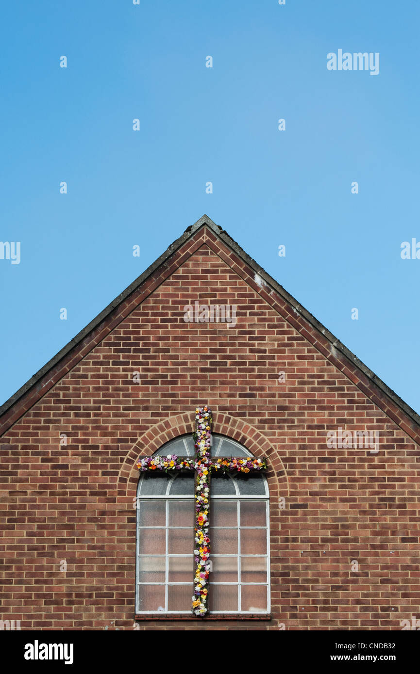 Croce di Pasqua e fiori su una chiesa cristiana evangelica. Banbury, Oxfordshire, Inghilterra Foto Stock